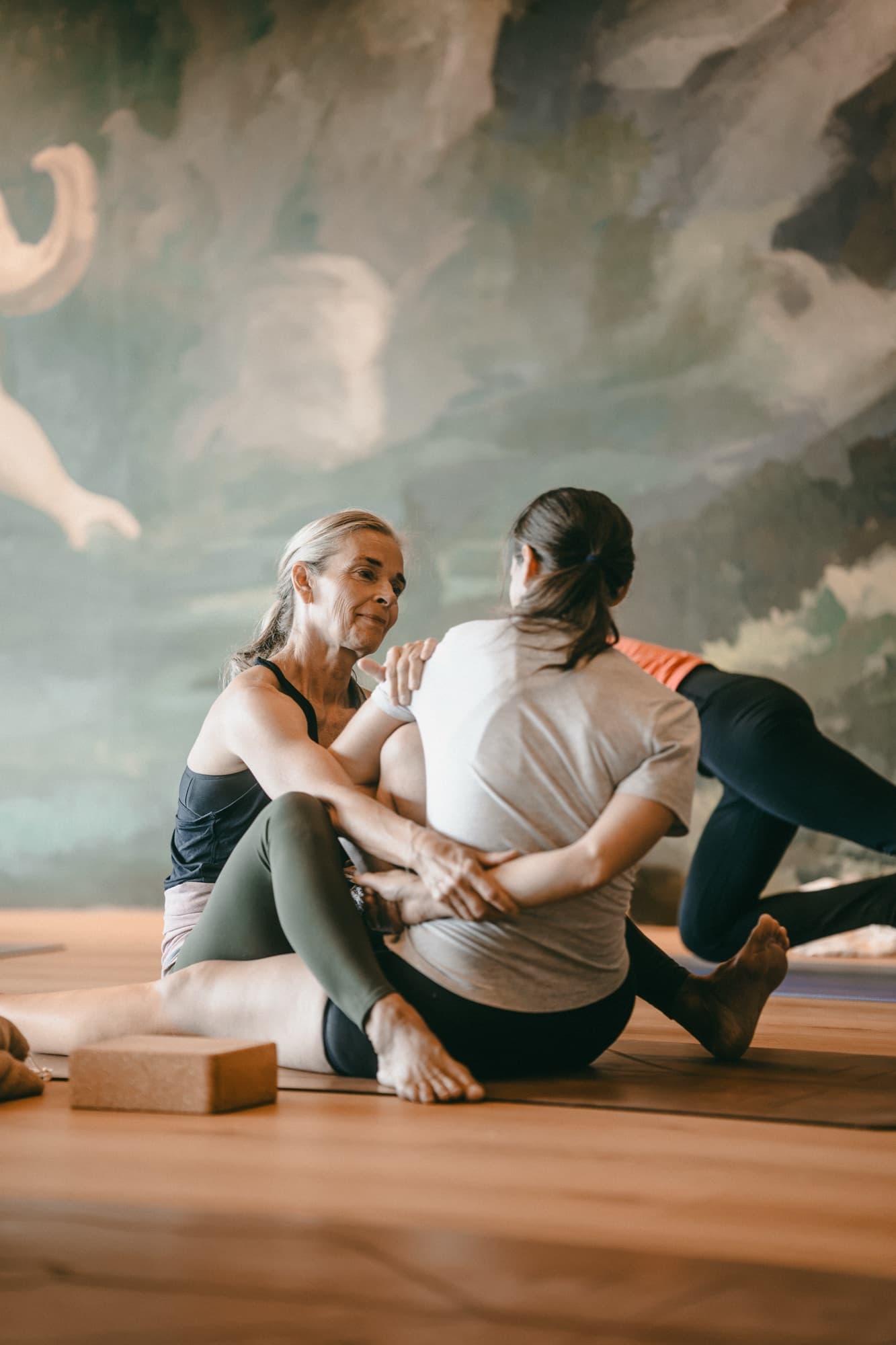 Lotta assisting a student in a seated twist