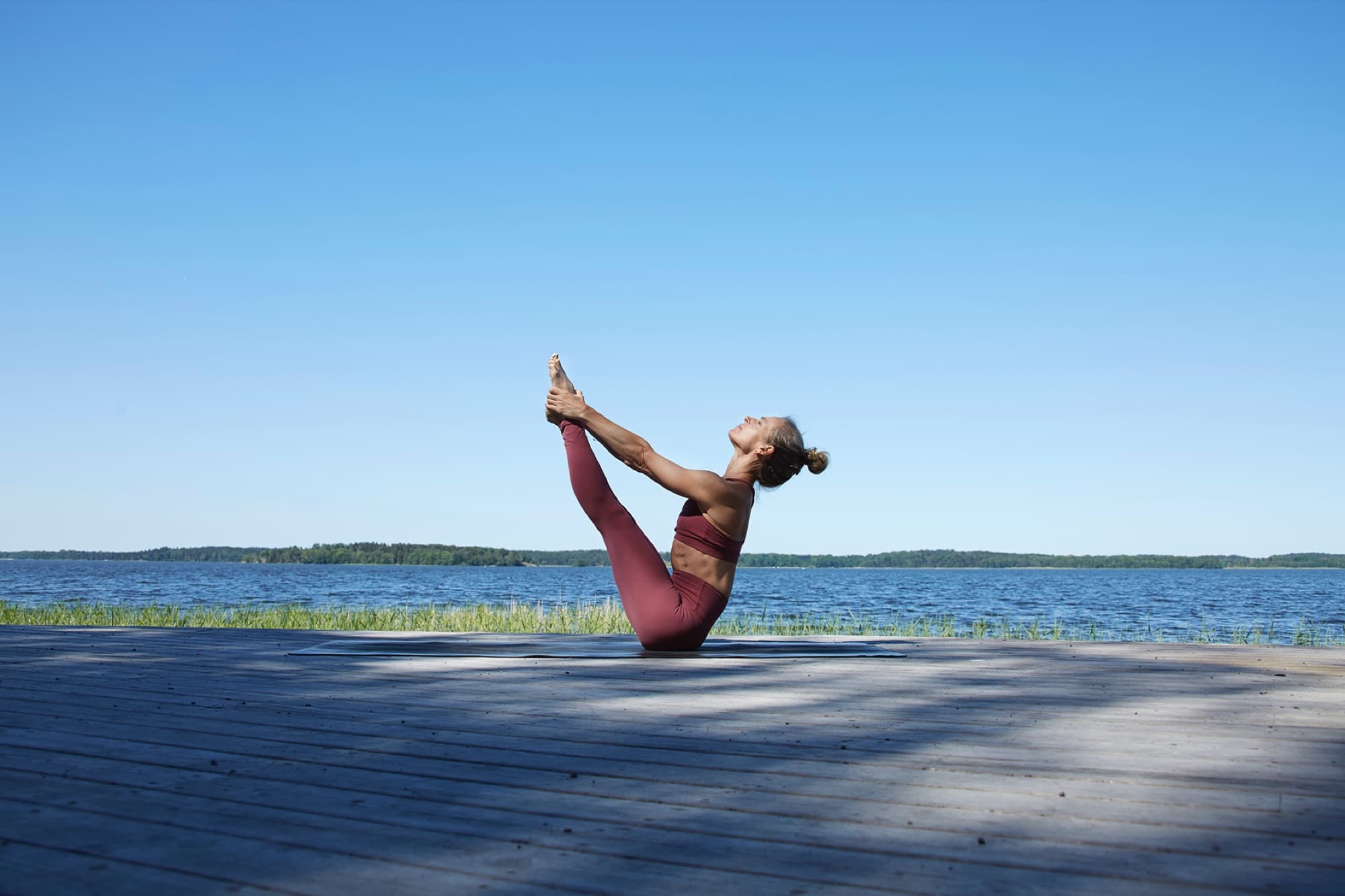Lotta in boat pose on a lakeside dock